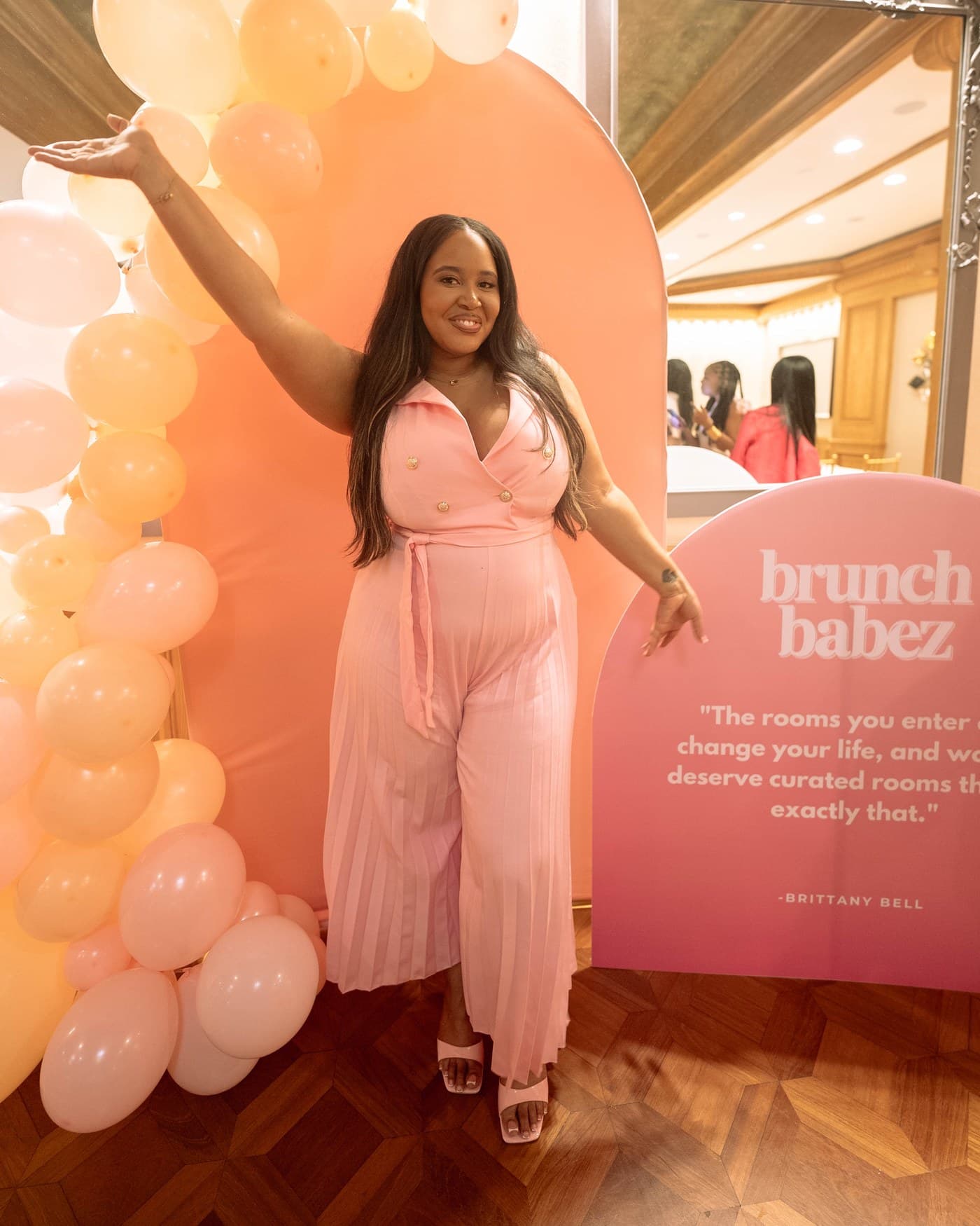 A guest with her arm raised at the balloon arch.