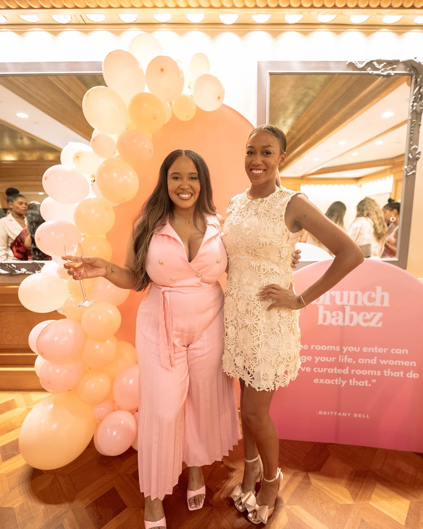 Two guests at the Brunch Babez backdrop in blush and cream.